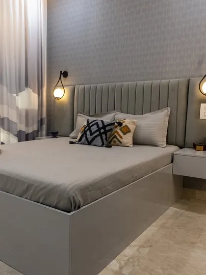 A calm guest bedroom with cool grey tones, a seamless vertical-paneled headboard, and a hidden bathroom door to maintain a clean and minimalist aesthetic.