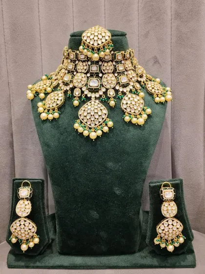 A stunning example of our Pachi Kundan work. This bridal set features intricate detailing with green bead and pearl accents, shown here on the mannequin before being worn by our beautiful bride.