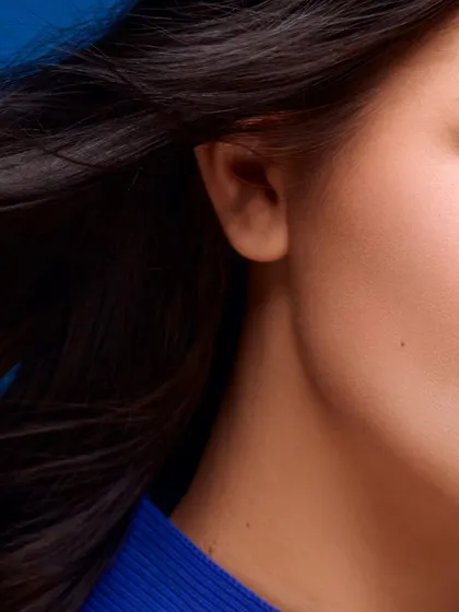 A partial face close-up for a beauty editorial. This composition creates a sense of mystery and artistry, focusing on the texture of the hair and the smooth skin.