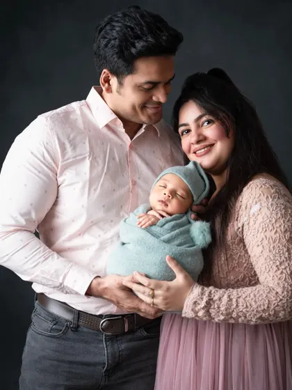 A new family of three, with parents lovingly gazing at their peacefully sleeping newborn.