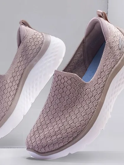 A pair of women's Skechers Go Walk shoes appearing to float in front of a mirror. This technique adds a sense of lightness and sophistication to the product, perfect for marketing comfortable footwear.