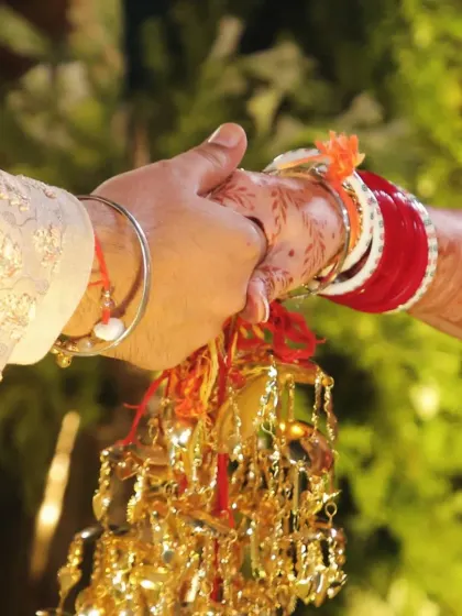 A close-up shot capturing the moment the couple holds hands during the wedding rituals, symbolizing their lifelong bond.