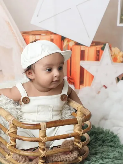 This little one is sitting up in a basket, surrounded by soft white clouds. This setup is ideal for babies around the 3-month mark, capturing their adorable expressions in a safe and cozy environment.