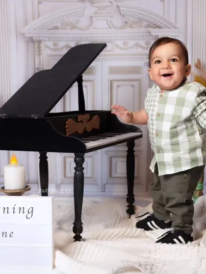 A happy one-year-old is ready to play some tunes on our miniature grand piano in this musical-themed shoot.