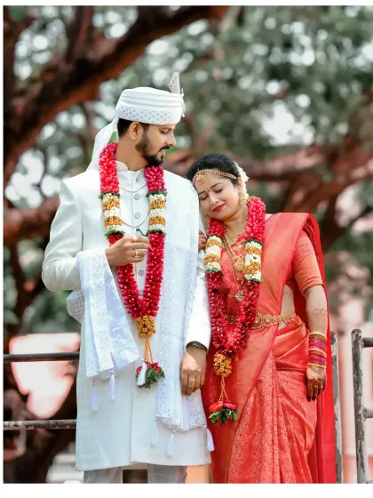 A tender moment between the couple, standing close together in their beautiful red and white wedding outfits.