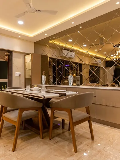 The dining area exudes opulence with a large table, comfortable seating, and a statement mirror wall that makes the space feel grand and bright.
