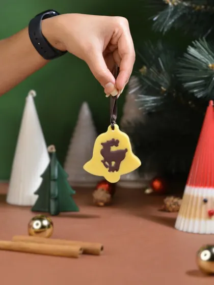 A yellow, bell-shaped Christmas ornament featuring a reindeer silhouette. These scented sachets are a unique way to decorate your tree and fill your home with holiday fragrance.