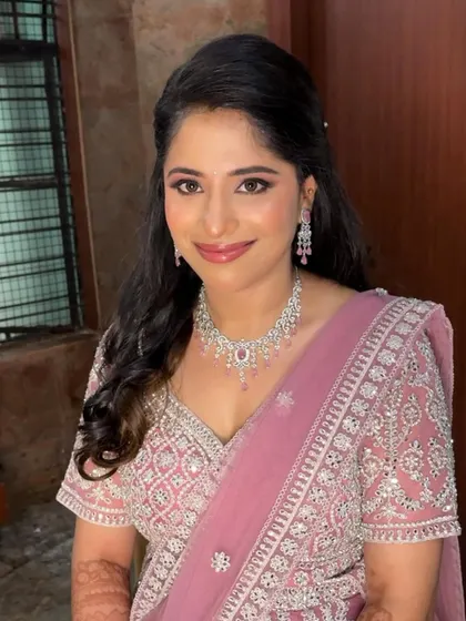 A close-up of Harshitha's reception makeup. The focus is on her bright smile and the soft, shimmering eye makeup that makes her features pop.