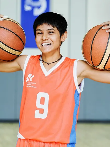 The pure joy of the game. A young player proudly holding two basketballs.