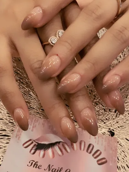 A moody and sophisticated ombre on long, almond-shaped nails. This set features a beautiful gradient from a sheer nude base to a deep brown at the tips.