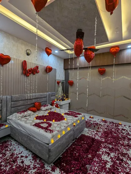 The same romantic room setup from a different angle, showing the full effect of the floating balloons, fairy lights, and the petal-covered floor.