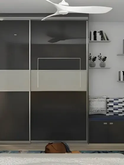 This bedroom features a sleek, wall-to-wall sliding wardrobe with glossy black and grey panels. Next to it, we added a cozy reading nook with a built-in bench and bookshelves, demonstrating our ability to combine storage with comfort.