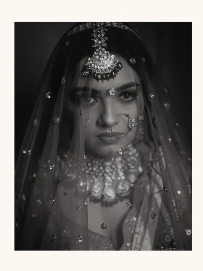 A timeless black and white portrait. The monochrome tones emphasize the bride's expressive eyes and the texture of her veil, creating a classic, soulful image.