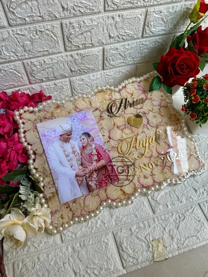 For this 12x16 inch frame, I used petals and pearls from the couple's actual varmala. The pearls form the zigzag border, and the petals fill the background behind their photo and names.