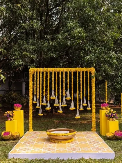This outdoor Haldi ceremony setup is perfect for a garden or lawn event. The simple wooden frame is decorated with hanging strings of bright yellow marigolds, creating a beautiful and auspicious space for the ritual.