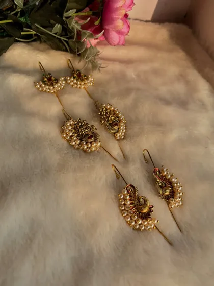 A flat-lay of our collection of Maharashtrian ear pins (karnful). You can see the variety in designs, from simple studs to elaborate peacock motifs.