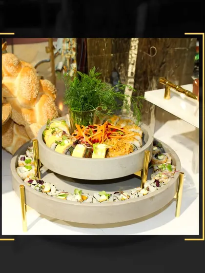 A two-tiered serving platter featuring a variety of fresh sushi rolls, demonstrating a modern and stylish way to present appetizers at a corporate event.