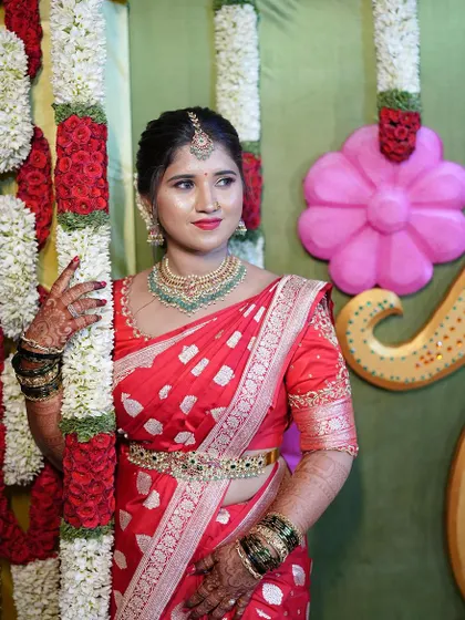 A beautiful client in a red saree, looking elegant with our green-beaded Kundan necklace.