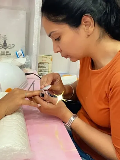 A student practices applying polish to a client's nails, focusing on precision and care.