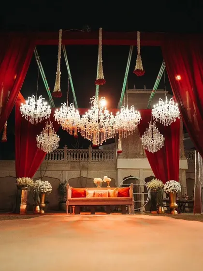 A dramatic photo spot with cascading chandeliers against a backdrop of deep red curtains, offering guests a glamorous setting for pictures and adding to the overall opulent decor.