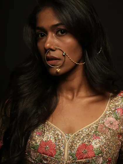 A close-up portrait focusing on the large traditional nose ring and the clean, flawless makeup on the model.