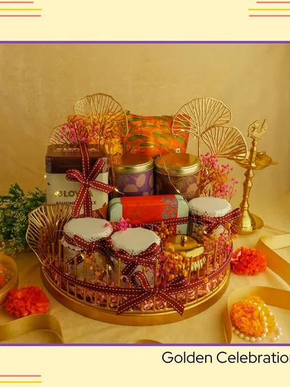 An example of a "Golden Celebration" hamper for Diwali. This arrangement features a golden tray filled with jars of goodies and adorned with decorative fans, creating a truly luxurious festive gift.