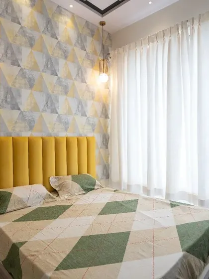 Sunny vibes in this bedroom, featuring a bright yellow headboard that pops against a geometric wallpaper. The white curtains keep the space feeling light and airy.