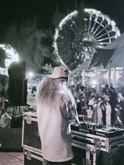 A black and white shot of me at the decks with a Ferris wheel in the background, capturing the classic festival atmosphere.
