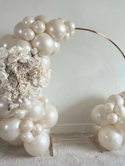 A chic and minimalist balloon arch with pearl-white balloons and a beautiful white floral arrangement, perfect for an elegant engagement or bridal shower.
