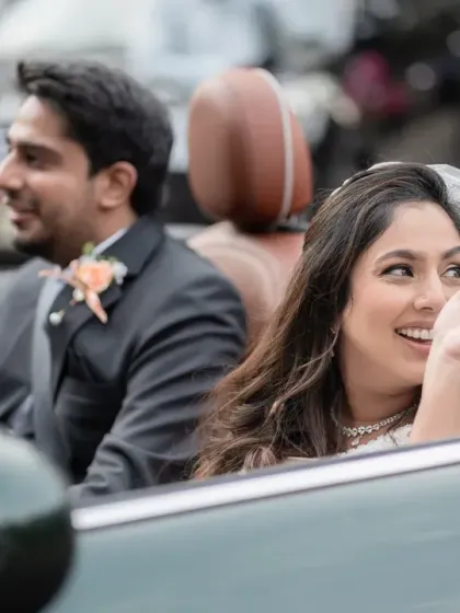 A close-up of the bride waving from the convertible, her face full of joy and excitement. This shot captures the happy "just married" feeling perfectly.