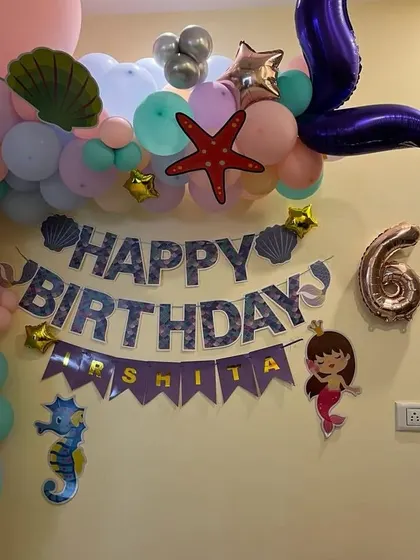 A close-up of the "Happy Birthday" banner and the top of the mermaid balloon arch, featuring a mermaid tail.