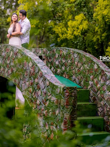 A romantic moment on a picturesque stone bridge. The couple's light-colored casual wear looks fresh and natural against the lush green surroundings.