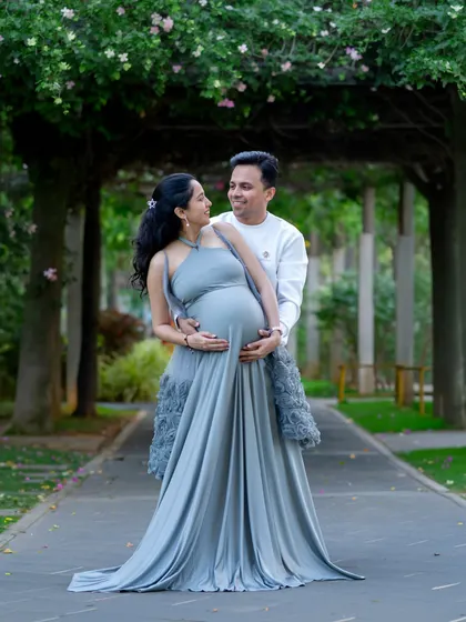 A romantic outdoor portrait of an expecting couple, framed by a beautiful floral archway.