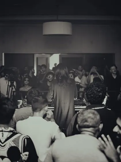 A black and white shot capturing the intimate, focused energy of the crowd gathered around the center stage for a mind-bending set by a guest artist.