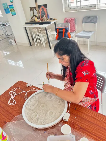 A guest carefully working on her moon lamp, creating craters and texture for a realistic look.
