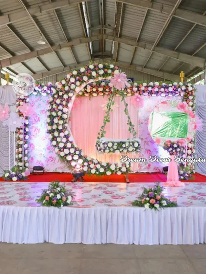A wide shot of the moon cradle naming ceremony setup in a large hall. This shows how the decor can fill a stage and create a magnificent focal point for the event.