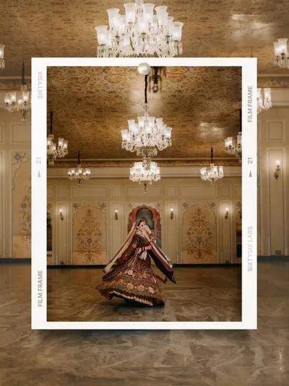 An artistic shot of a bride twirling in a grand ballroom, her lehenga in full flare, framed like a film still.