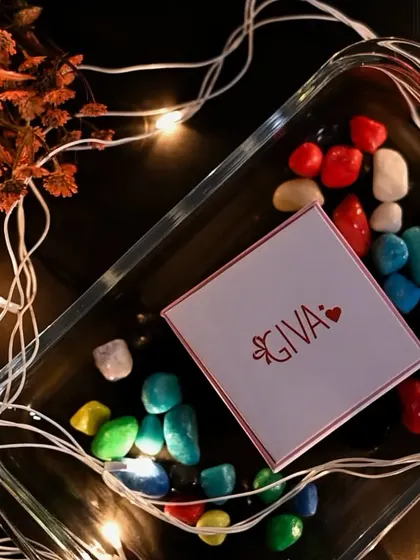 A flat-lay product shot for a jewelry brand. The colorful stones and fairy lights create a festive and attractive setting for the product box, ideal for promotional content.