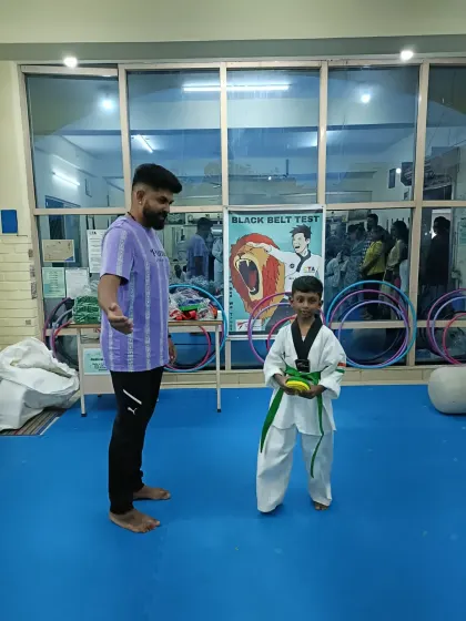 A student proudly holds his new green belt.
