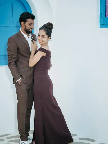 A stylish and modern pre-wedding portrait. The clean white and blue background makes the couple's coordinated outfits pop, creating a fresh and contemporary look.