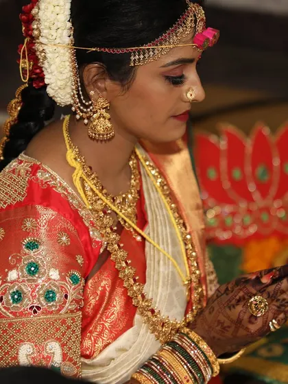 A closer look at Madhura's hands during the puja, the deep henna stain adding to the sanctity of the moment.