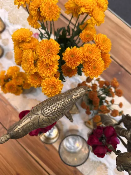 A close-up of our brass decor elements, like these bird-shaped candle holders, mixed with fresh marigolds.
