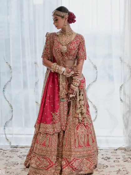 A classic full-length portrait of the bride in her magnificent red and gold lehenga, radiating timeless elegance.