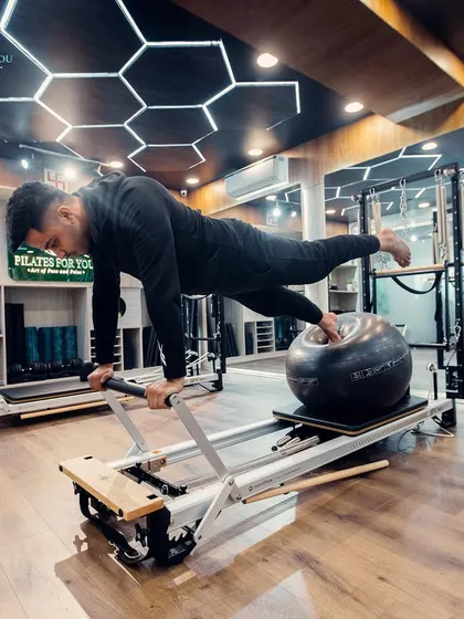 For those looking to advance their practice, we incorporate stability challenges like this high plank on the Reformer using an exercise ball. This move requires immense core control, balance, and full-body strength.