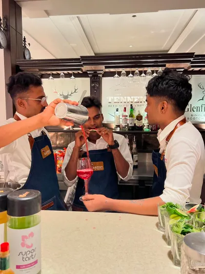 Our bartenders working together seamlessly behind a classic wooden bar. This photo shows the camaraderie and professionalism that defines our service.