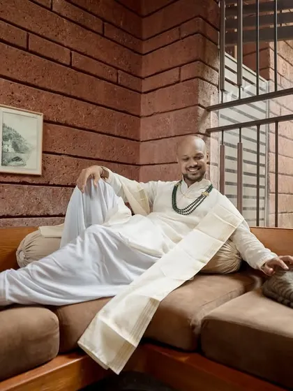A relaxed portrait of the groom-to-be, comfortably lounging in his traditional white kurta, even sharing a moment with a furry friend.