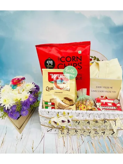 A thoughtfully curated birthday basket for him. It includes a small floral arrangement, corn chips, tiramisu wafers, and a fun "Every pizza me loves every pizza you" card.
