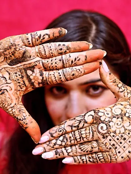 A beautiful bride framing her face with her freshly done mehandi. The joy on her face says it all.