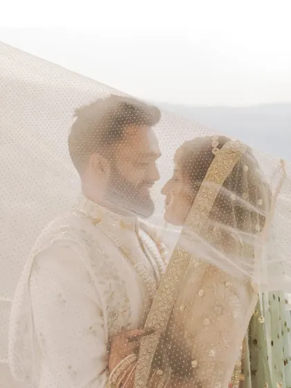 A tender moment between the couple, captured through the bride's veil, creating a soft and intimate portrait.