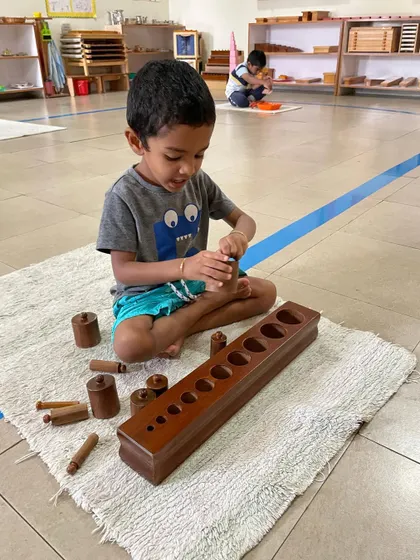 The Cylinder Blocks are a foundational sensorial material. By fitting each cylinder into its correct socket, the child refines their pincer grip for writing and develops their ability to visually discriminate between different dimensions.